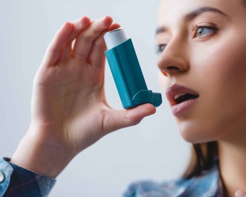 close-up-view-of-young-woman-with-asthma-using-inh-DYEHUDX_11zon